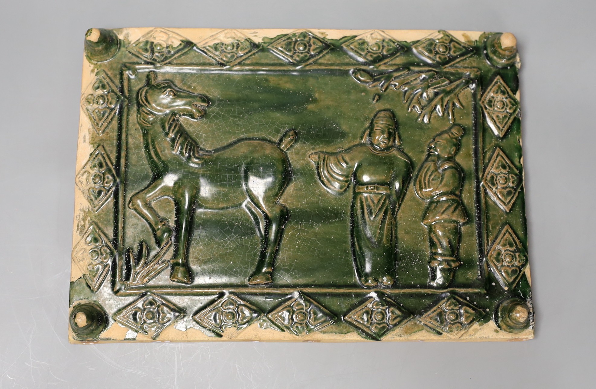 A 19th century Chinese green glazed tile with figures and a horse, 19 x 27cm